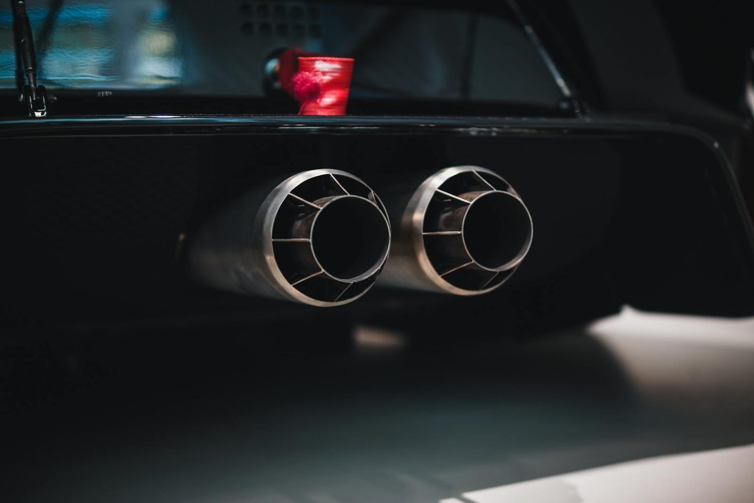 Close-up shot of dual exhaust pipes on a sleek car, with a focus on detail and design.