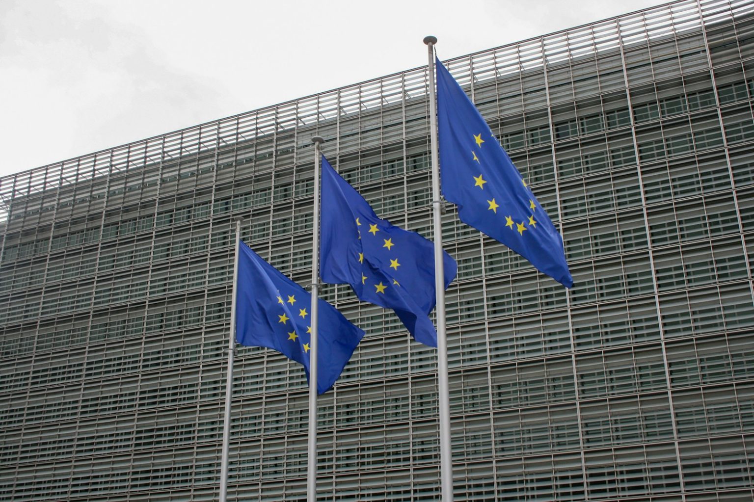 three european flags flying in front of a building