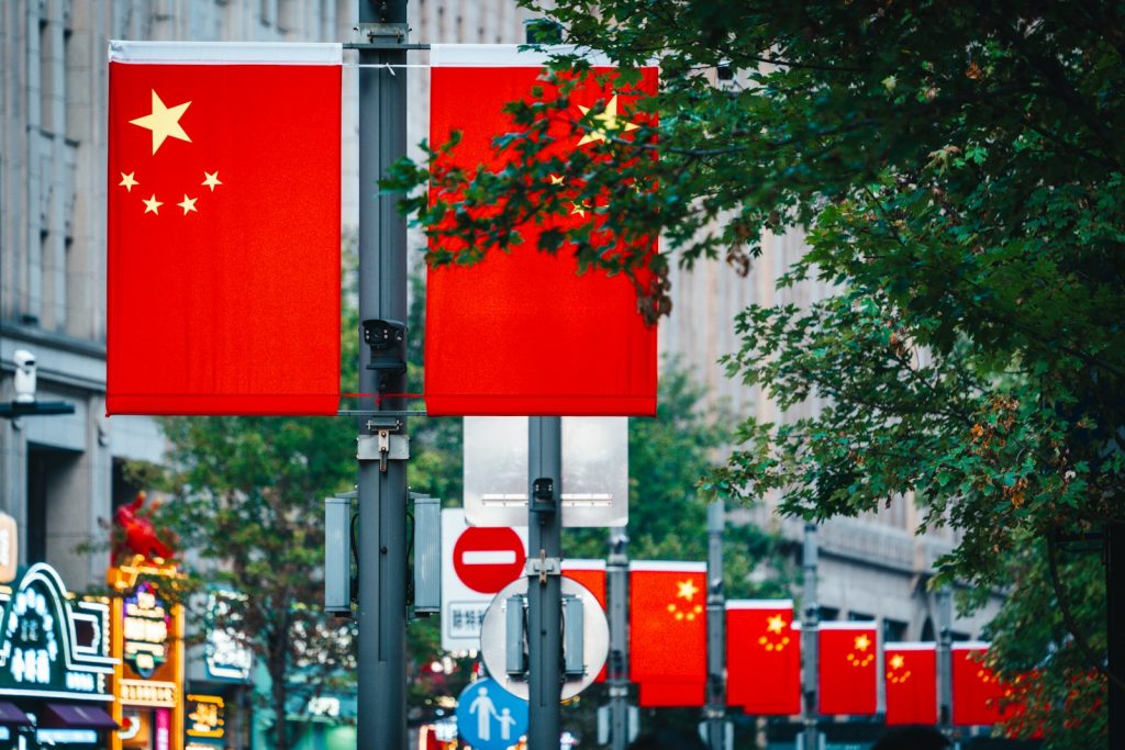 Chinese flags displayed on a street with trees.