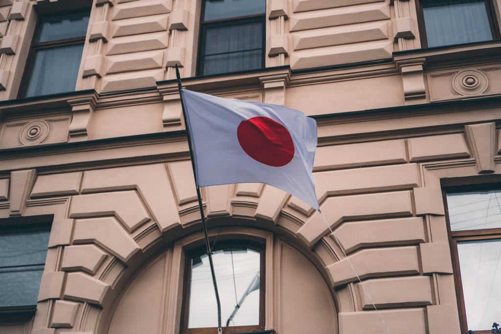Japan Plans New EV and PHEV Tax From 2028 as EV Market Evolves white red and black flag on brown concrete building during daytime