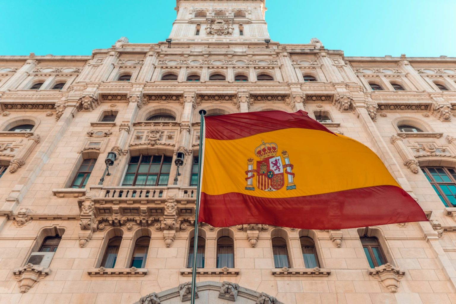 Spain’s Public EV Charging Network Reaches 50,000 Points as Fast Chargers Multiply flag on pole beside building during day