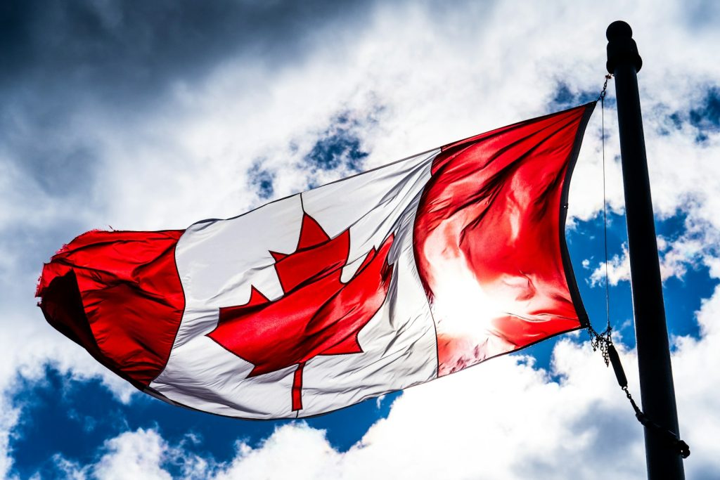 Canada–China EV Tariff Deal Seen Benefiting Tesla, Volvo and BYD red and white flag under blue sky during daytime