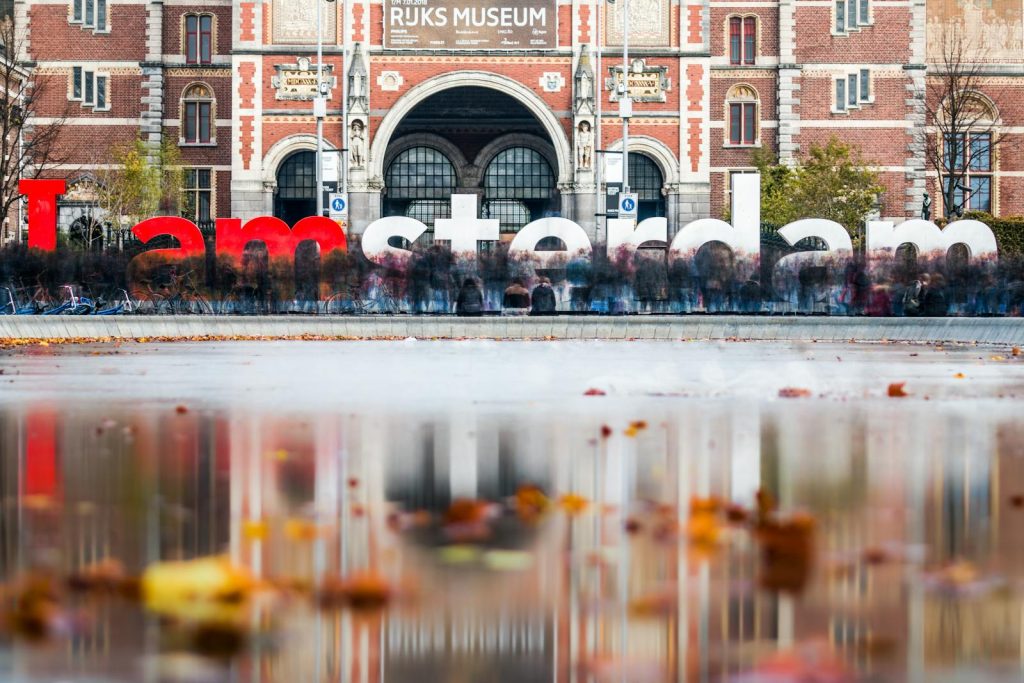 The famous I amsterdam sign in front of the Rijksmuseum with autumn reflections in the foreground.