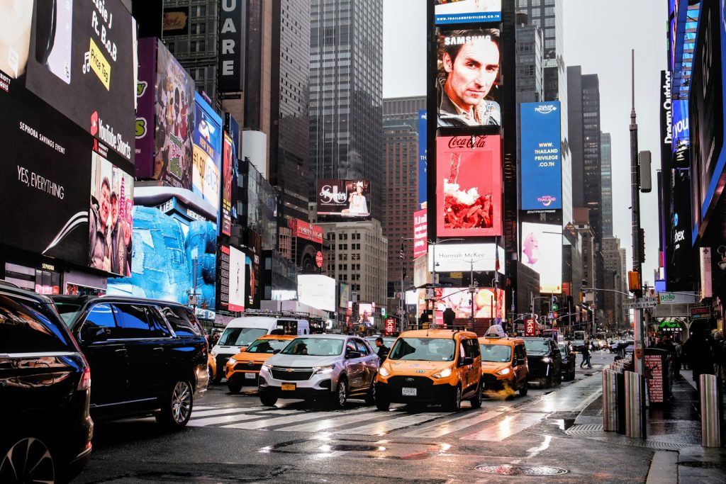 Busy times square with traffic and bright signs.