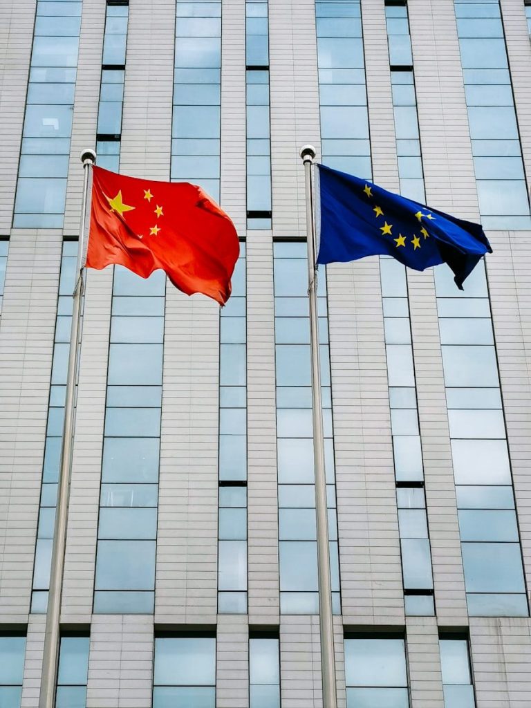 two flags flying next to each other in front of a building