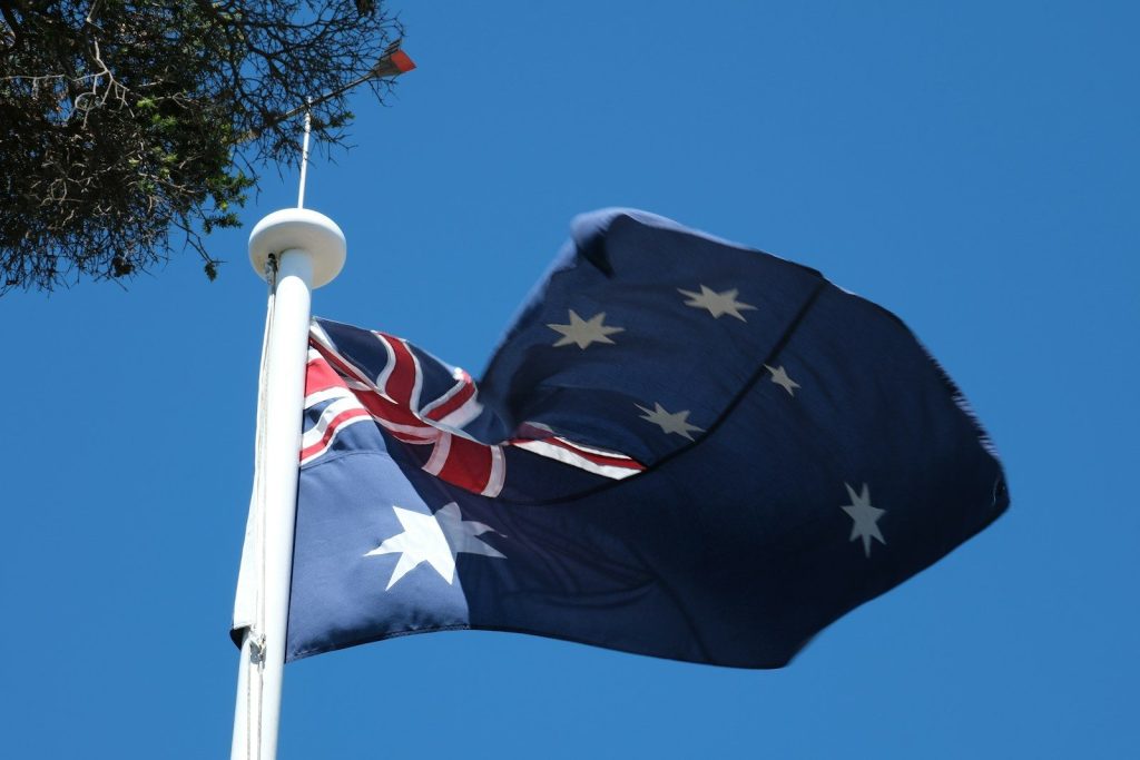 EU and Australia Strike Trade Deal to Boost EV and Battery Supply Chains A flag flying high in the sky next to a tree
